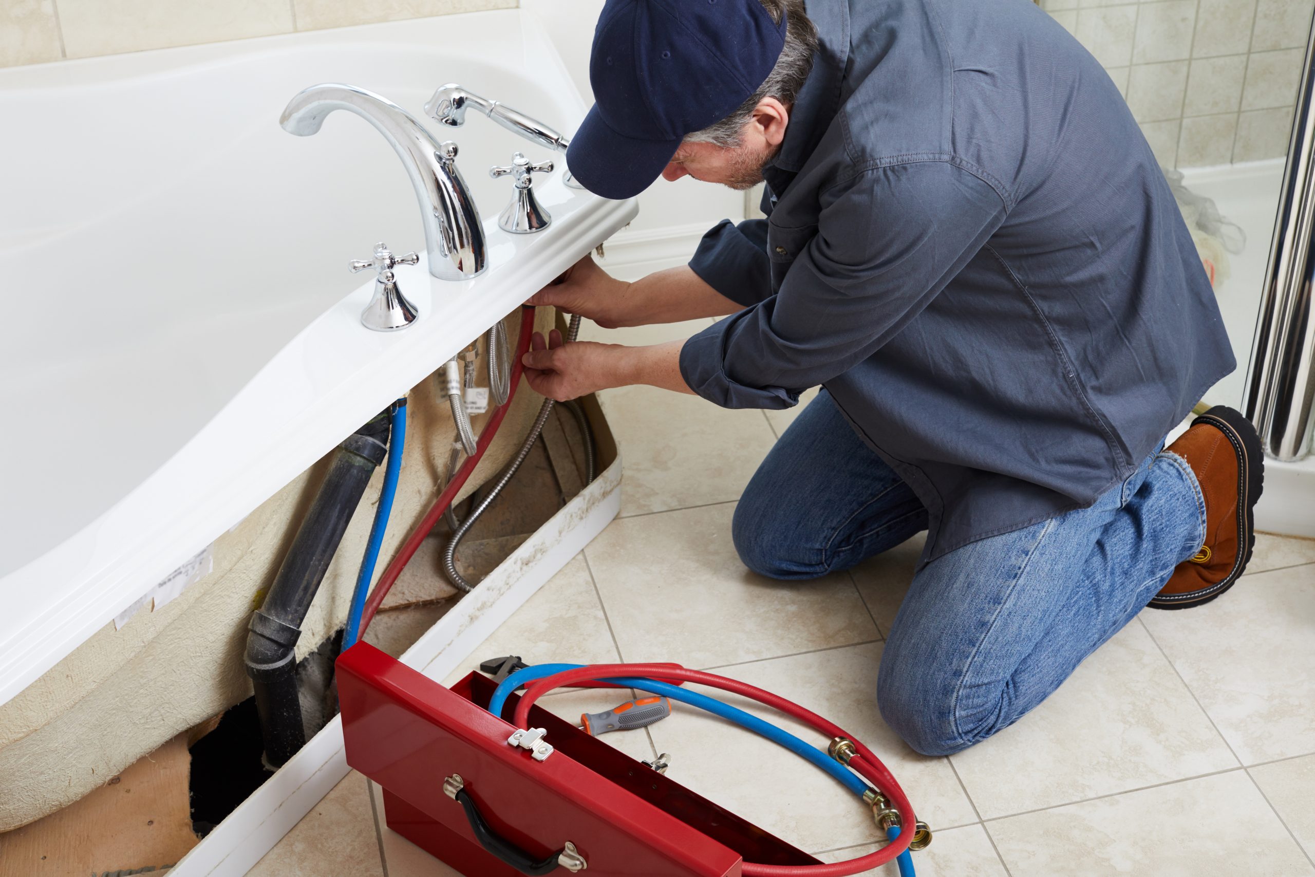 Professional plumber doing plumbing renovation in bathroom.